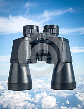 Binoculars with blue sky and clouds reflected in the lenses - future vision metaphor