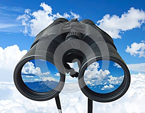 Binoculars with blue sky and clouds reflected in the lenses - future vision metaphor