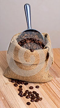 A sack of roasted coffee beans in a metal scoop studio.