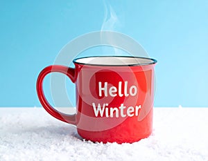 Red mug with words Hello winter on the blue background.