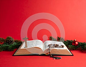 Christmas red background with Bible and rosary on the table