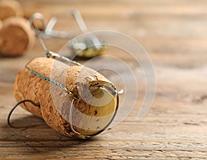 Cork of sparkling wine and muselet cap on wooden table, closeup. Space for text