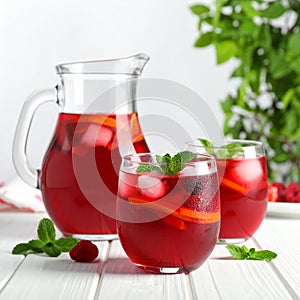 Glasses and jug of Red Sangria on white wooden table