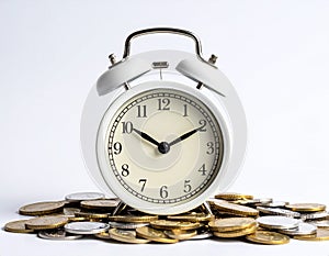 White alarm clock on golden and silver coin on white background. investing and finance