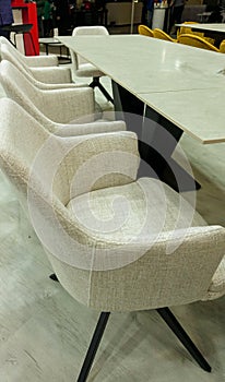 Classic armchairs upholstered in gray fabric stand behind a long table. photo
