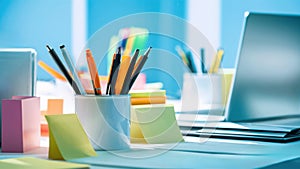 A desk with a laptop, pencils and post it notes, AI