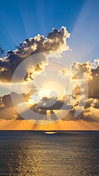 Dramatic sunset over the ocean with sun rays breaking through the clouds