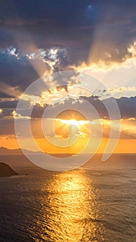 Dramatic sunset over the ocean with sun rays breaking through the clouds