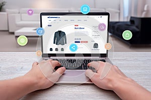 Hands typing on laptop, shopping online for men's blazer with levitating shopping icons photo