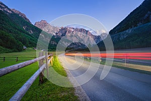 Road in Alpine mountains at twilight with blurred light trails photo