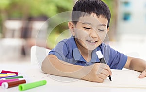 Smiling asian child schoolboy studying and writing at home photo