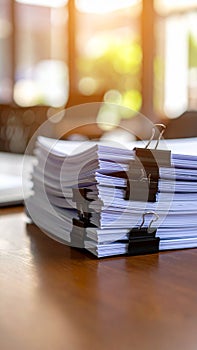 Stack of Documents Secured by Black Binder Clips on Wooden Table