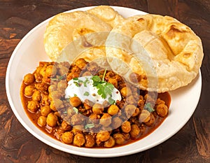 Classic North Indian dish of Chole (chickpea curry) and Bature (deep fried leavened bread). Generated image