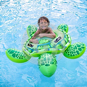 Generated imageCute smiling young African American boy playing happily in a swimming pool with an inflatable turtle toy.