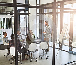 Generating new ideas together. Shot of a businessman giving a presentation to his coworkers in a modern office.