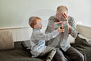 Generation. grandfather and grandson with gift box sitting on couch at home