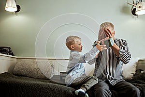 Generation. grandfather and grandson with gift box sitting on couch at home