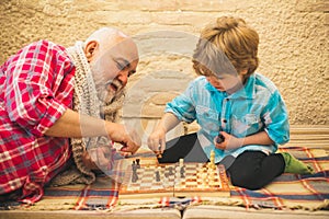 Generations. Checkmate. Chess hobbies - granddad with grandson on a playing chess.