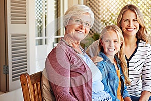 Through the generations. Cropped portrait of a young girl sitting outside with her mother and grandmother.