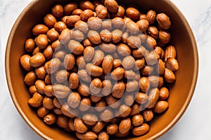 Roasted peanuts in white bowl on wooden background. Close up. Generative AI