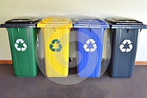 Generative AI. Four color-coded recycling bins lined up against a wall, each marked with recycling symbols