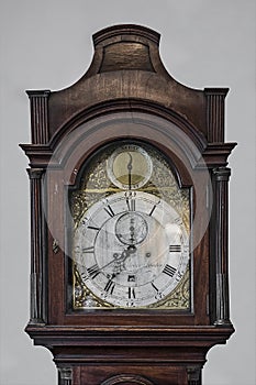 Generic antique old wood and brass grandfather clock face shot straight on that`s no longer manufactured.