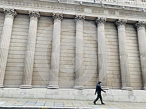 Generic architecture pillars in London and a man walking on the street