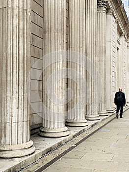 Generic architecture pillars in London and a man walking on the street