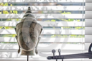 Generic buddha head statue on summer windowsill with electric violin