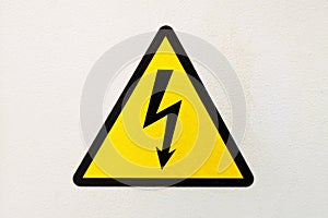Generic high voltage danger sign, symbol. Sign of danger high voltage symbol on the white wall. Warning icon