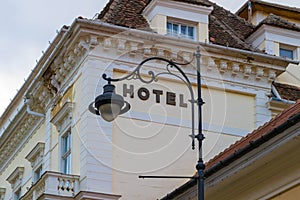 Generic hotel sign framed by an artistically curved street lamp, with renovated old buildings in the background.