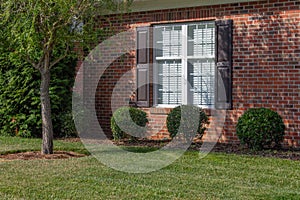 Generic house with red brick, white window with brown shutters