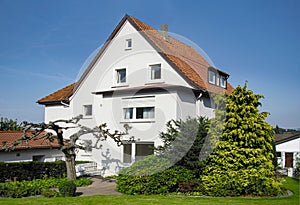 generic old family house in Germany with white facade and garden in front