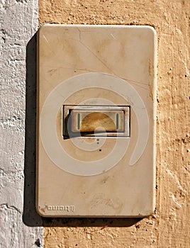 Generic old light switch being hit by sunlight and deteriorated yellow plastic from time passing