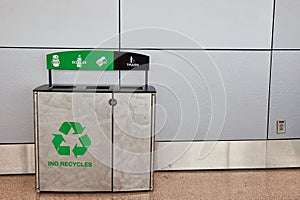 Generic recycling receptacle with trash section against long gray wall with Ind Recycles slogan