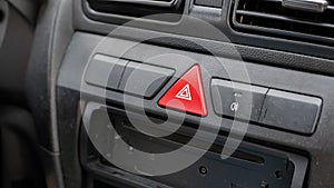 Generic red triangle emergency stop hazard lights button on a car dashboard, car interior object detail closeup, nobody. Vehicle
