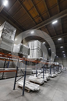 Generic warehouse industrial interior with palettes stacked on shelves. Wide angle view