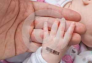 Genetic clone concept. Man is holding hand of a baby with bar co photo