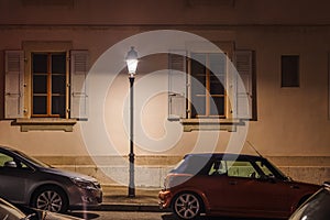 Geneva old-style classical residential building facade with street light and cars parked along the street during summer night,