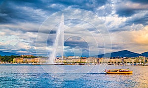 Geneva skyline with famous Jet d`Eau fountain and boat at sunset