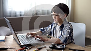 Genius child in safety glasses searching online instructions to PC details