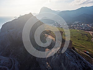 Genoese fortress in Sudak, Crimea. Aerial panorama view of ruins of ancient historic castle on crest of mountain near sea