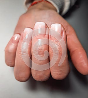 Gentle camouflage gel nail polish with a white gradient. Hands with a professional manicure. photo