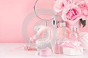 Gentle girlish dressing table with round mirror, flowers and cosmetics products - rose oil, bath salt, cream, perfume.