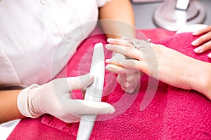 Gentle hands of manicurist taking care of pretty nails