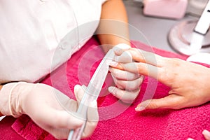 Gentle hands of manicurist taking care of pretty nails