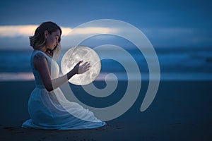 Gentle image of a girl, Astrology, Female magic. Beautiful attractive girl on a night beach with sand hugs the moon, art