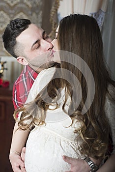 A gentle kiss-happy couple awaiting the birth of their child.