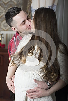 A gentle kiss-happy couple awaiting the birth of their child.