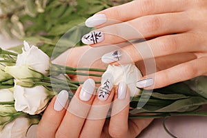 Gentle neat manicure on female hands on flowers background. Nail design